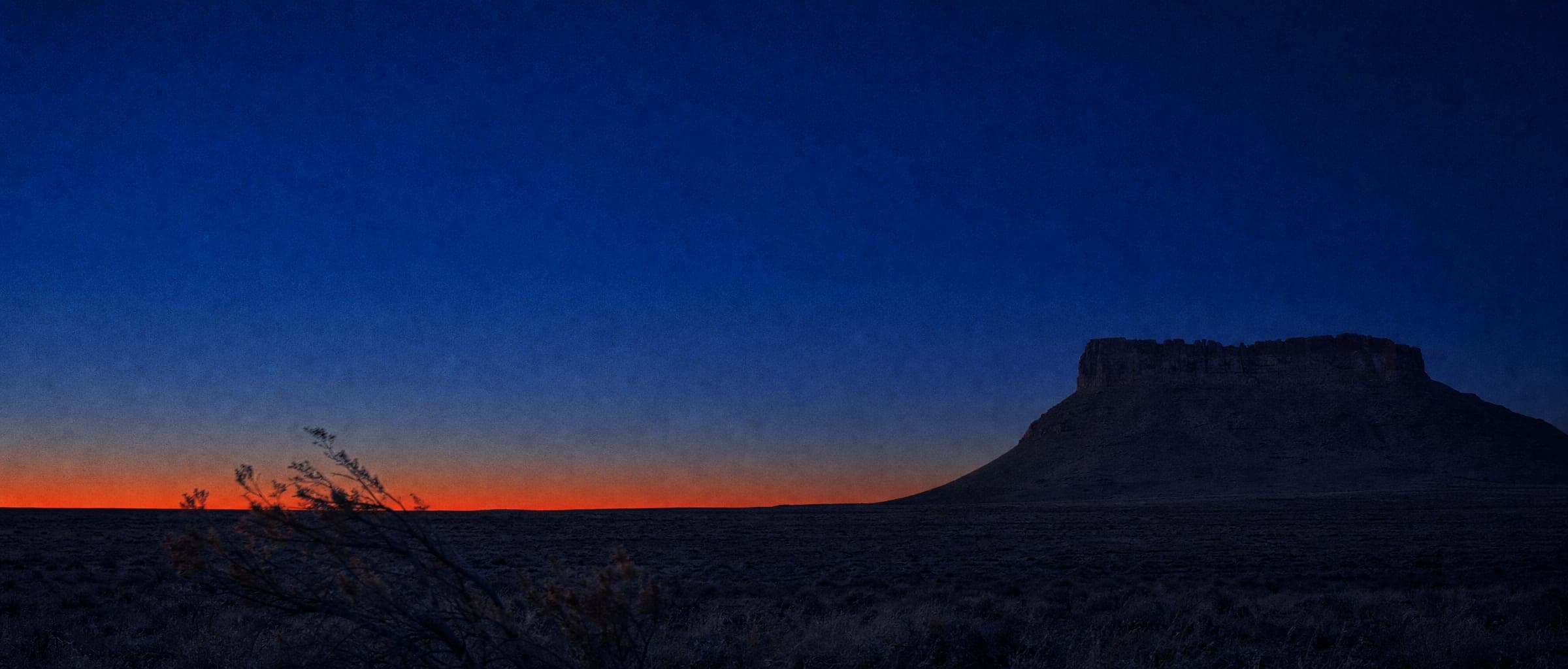 New Mexico high-desert mesa at blue hour, under a last band of light on the horizon, evoking the 'Terra' in Kipu Terra.